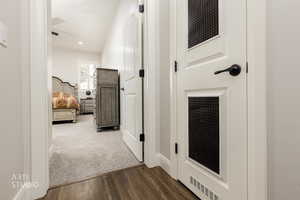 Corridor with dark wood finished floors and dark carpet