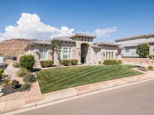 View of front of property featuring a tile roof, a front lawn, and stucco siding