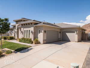 View of front of home with stucco siding, driveway, an attached garage, a tiled roof, and a front yard