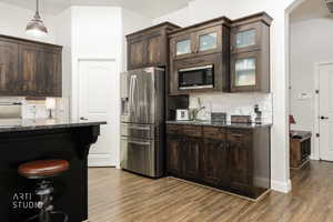 Kitchen featuring dark brown cabinets, decorative backsplash, and dark stone counters