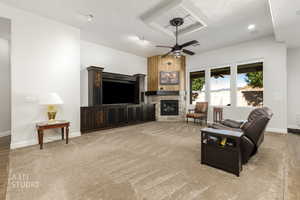 Living room with light colored carpet, a stone fireplace, a textured ceiling, and ceiling fan