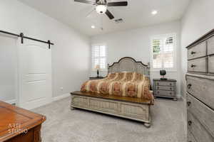 Bedroom with a barn door, light colored carpet, a ceiling fan, and recessed lighting