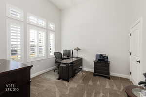 Home office featuring dark carpet and a high ceiling