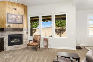 Carpeted living area featuring healthy amount of natural light, a fireplace, and wood walls
