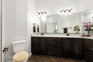 Bathroom with double vanity and dark wood-type flooring
