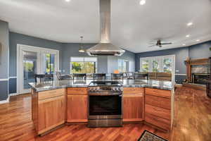 Kitchen featuring stainless steel range with electric stovetop, ceiling fan, recessed lighting, a high end fireplace, and island exhaust hood