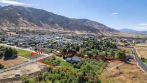 Aerial view of residential area with property parcel outlined and a mountain backdrop