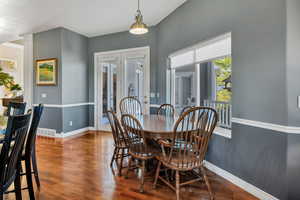 Dining area with wood finished floors, french doors, and decorative columns