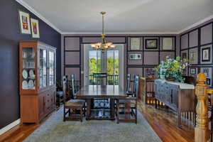 Formal Dining room with a chandelier, crown molding, wood finished floors, and a decorative wall