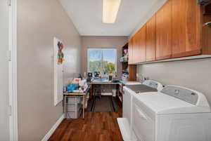 Laundry room  featuring dark wood finished floors, washer and clothes dryer, and a desk