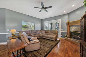 Living area with dark wood-style floors, a high end fireplace, recessed lighting, and a ceiling fan