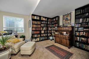 Bedroom /office  with wall of books and light colored carpet