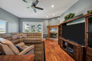 Living room with light wood-type flooring, recessed lighting, ceiling fan, and a high end fireplace