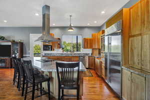 Kitchen with an expansive granite kitchen breakfast bar ,  light wood finished floors, and recessed lighting