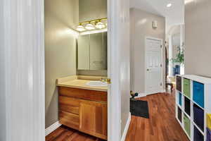 Half bathroom with dark wood-style flooring, vanity, and recessed lighting