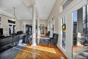 Entryway featuring ornate columns, french doors, wood finished floors, crown molding, and healthy amount of natural light