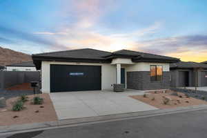 Prairie-style home with a tiled roof, stucco siding, driveway, and an attached garage