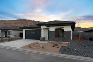 Prairie-style home featuring stucco siding, concrete driveway, a tile roof, stone siding, and a garage