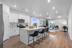 Kitchen with a center island, recessed lighting, a raised ceiling, white cabinetry, and a kitchen bar