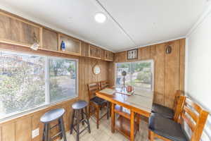 Dining space featuring wood walls, light tile patterned floors, and ornamental molding