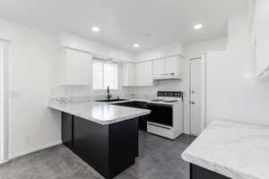 Kitchen with light countertops, a peninsula, white appliances, white cabinetry, and recessed lighting