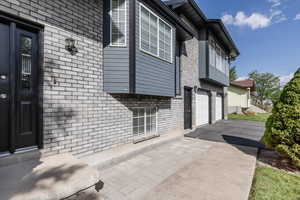 View of property exterior featuring brick siding, asphalt driveway, and an attached garage