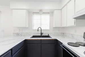 Kitchen with white electric range, light countertops, and white cabinetry