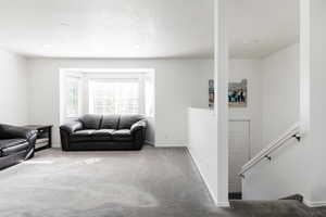 Carpeted living area with baseboards and a textured ceiling
