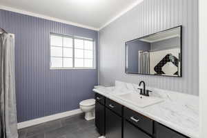 Bathroom featuring dark tile patterned floors, vanity, ornamental molding, and curtained shower