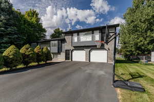 View of front of house featuring driveway, an attached garage, and brick siding