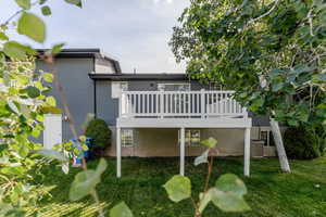 Rear view of house featuring a yard and a wooden deck