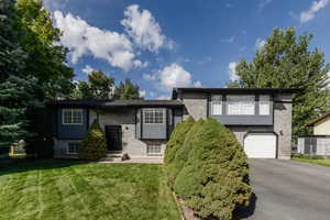 View of front of property featuring brick siding, asphalt driveway, an attached garage, and a front yard