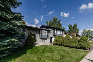 Bi-level home with brick siding, a patio, and a front yard