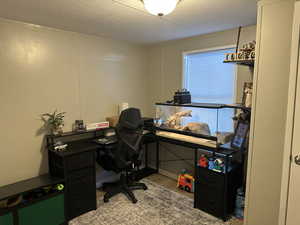 Office with a decorative wall, light wood-style floors, and a textured ceiling