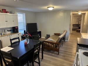 Dining room with a decorative wall, light wood-type flooring, and a textured ceiling