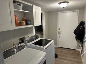 Washroom featuring dark wood-style flooring, cabinet space, a textured ceiling, and independent washer and dryer