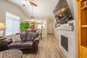 Living area featuring a ceiling fan, a fireplace, light LVP floors, recessed lighting, and vaulted ceiling