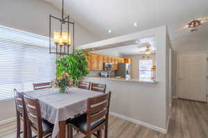 Dining space featuring recessed lighting, light wood-style flooring (LVP), lofted ceiling, a ceiling fan, and a chandelier
