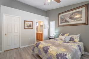 Primary Bedroom with light wood finished floors, ensuite bathroom, and ceiling fan