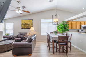 Dining room & Living room with lofted ceiling, light wood-type flooring, plenty of natural light, a ceiling fan, and a chandelier