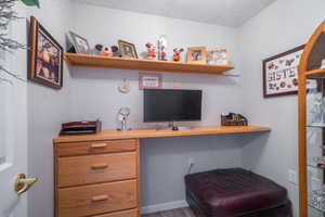 Office featuring a textured ceiling, built in desk, and wood finished floors