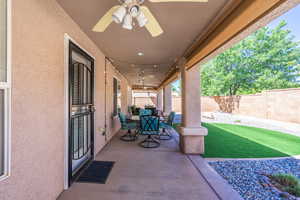 Fenced backyard with a ceiling fan, outdoor dining area, and a patio area