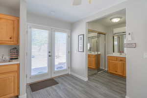 Entry with french doors to ADU with wood finished floors, a wall mounted mini-split AC, and a ceiling fan