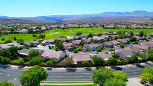 Aerial perspective of suburban area featuring a mountainous background and near-by golf course
