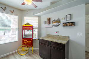 Kitchen fnook eaturing light LVP flooring, dark brown cabinet, light gramote counters, and bay windows to bring in plenty of natural light