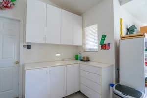 Corner of garage featuring white cabinetry and light countertops