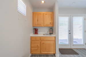 Wet Bar in casita.  french doors, light countertops, light brown cabinets, and light wood-style floors