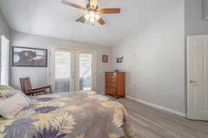 Primary Bedroom featuring access to outside, lofted ceiling, french doors, wood finished floors, and ceiling fan