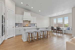 Kitchen featuring lofted ceiling, a kitchen bar, tasteful backsplash, a kitchen island with sink, and recessed lighting