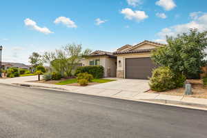 Mediterranean / spanish-style house with driveway, stucco siding, stone siding, an attached garage, and a tile roof